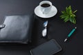 Black coffee, flora, pen, spectacles, mobile phone and organizer on black background Royalty Free Stock Photo