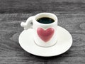 espresso shot in small coffee cup with embossed big purple heart and white saucer on dark gray rustic wooden table floor Royalty Free Stock Photo