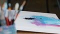 Close-up black dark paint splatters on canvas with pink and blue color picture female hand holding paint brush draws