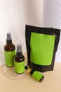 Close up black doy pack and three spray bottles with cosmetic product, green space for brand.