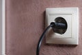 Close-up of a black electric plug in a 220 socket in the wall. Power on concept Royalty Free Stock Photo