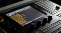 Close-up of a black electronic control panel or mixer device with multiple knobs and buttons and a large central screen displaying Royalty Free Stock Photo