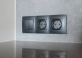 A close-up on black European socket, power outlet plug and light switch on a gray wall in the kitchen Royalty Free Stock Photo