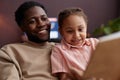 Close up Black father and daughter reading book at home and Royalty Free Stock Photo