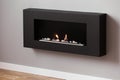 Black fireplace on grey wall in simple living room interior. Real photo