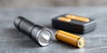 Close-up of a black flashlight with yellow rechargeable batteries and charger on a gray surface in soft focus background Royalty Free Stock Photo