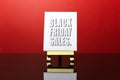 Close-up of black friday sales text, on the small easel. Background of red color.