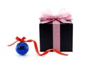 black gift box with glittering pastel pink ribbon net bow and glossy blue christmas ball with red ribbon Royalty Free Stock Photo