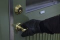 Close up of black gloves on safety door handle. Break-in - burglar - concept image.
