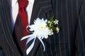 Close-up Black Jacket Groom On Their Wedding Day With A Red Tie And Lapel Buttonhole.