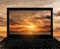 Close-up Black Laptop with landscape sunset at tropical ocean island on screen