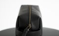 Close up black leather classic mens cosmetic bag with a metal gold zip on a black chair with a white background. Royalty Free Stock Photo