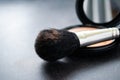 Close-up of a black makeup brush with flesh-colored powder at the end. On the background of an open box with a mirror and pink Royalty Free Stock Photo