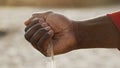 Close up, black man hand pouring sand. Low angle shot Royalty Free Stock Photo