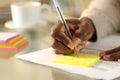 Black man hand writing on sticky note on a desk Royalty Free Stock Photo