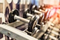 Close up of black metallic steel dumbbell set. Dumbbells on rack in sport fitness center. Workout training and fitness gym concept