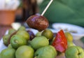 Close-up of Black Olive caught with a toothpick from spiced olives plate on tapas bar table typical Spanish green split