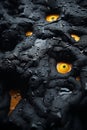 a close up of a black and orange rock with yellow eyes Royalty Free Stock Photo