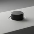 A close-up of a black round button embedded in a smooth, light gray surface. The Royalty Free Stock Photo