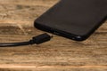 Close-up of black smartphone charging battery with an USB cable on wooden table with copy space Royalty Free Stock Photo