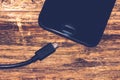 Close-up of black smartphone charging battery with an USB cable on wooden table with copy space Royalty Free Stock Photo