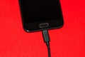 Close-up of black smartphone charging battery with an USB cable on wooden table with copy space Royalty Free Stock Photo