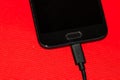 Close-up of black smartphone charging battery with an USB cable on wooden table with copy space Royalty Free Stock Photo