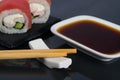 Close-up, on a black table with a reflection, Japanese rolls with cream cheese, tuna and cucumber, next to wooden sticks and a Royalty Free Stock Photo