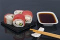 Close-up, on a black table with a reflection, Japanese rolls with cream cheese, tuna, shrimp and cucumber, next to wooden sticks Royalty Free Stock Photo