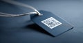 Close-up of a black textured price tag with a QR code attached to a twisted silver string on a dark fabric surface Royalty Free Stock Photo