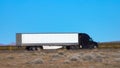 CLOSE UP: Black truck speeds along the interstate highway crossing a desert Royalty Free Stock Photo