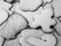 A close up black and white food photograph of a pile of baked sugar Christmas cookies in various shapes including gingerbread man