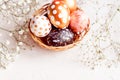 Close up of black, white and golden decorated eeaster eggs in wicker basket decorated with gypsophila on white background. Copy