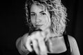 Close up black and white portrait of a beautiful young woman with blonde and curly hair pointing with the index finger Royalty Free Stock Photo