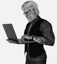 Close-up black and white portrait of a handsome tattooed silver fox with hipster glasses working on a laptop on an isolated white Royalty Free Stock Photo