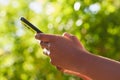 Close up of Black woman's hands using mobile phone, texting in nature leaf bokeh Royalty Free Stock Photo