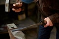 Close-up of a blacksmith`s hands manipulating a metal piece above his forge, selective focus. Royalty Free Stock Photo