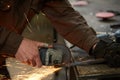 Close-up of a blacksmith`s hands manipulating a metal piece above his forge, selective focus. Royalty Free Stock Photo