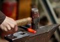 Close-up of a blacksmith`s hands manipulating a metal piece above his forge, selective focus. Royalty Free Stock Photo