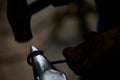 Close-up of a blacksmith`s hands manipulating a metal piece above his forge, selective focus. Royalty Free Stock Photo