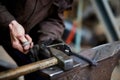 Close-up of a blacksmith`s hands manipulating a metal piece above his forge, selective focus. Royalty Free Stock Photo