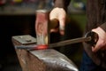 Close-up of a blacksmith`s hands manipulating a metal piece above his forge, selective focus. Royalty Free Stock Photo