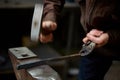 Close-up of a blacksmith`s hands manipulating a metal piece above his forge, selective focus. Royalty Free Stock Photo