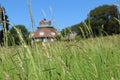 Close up of blades of grass with a blurred image of an unusual historic sixteen sided house on a beautiful sunny summers day in Royalty Free Stock Photo