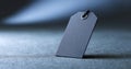 Close-up of blank black price tag with string on textured surface with soft blue lighting and shallow depth of field Royalty Free Stock Photo
