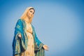 Close-up Of The Blessed Virgin Mary Statue Figure. Catholic Praying For Our Lady - The Virgin Mary. Blue Sky Copy Space On