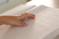 Blind boy hand reading a braille book in classroom