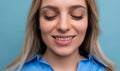 close-up of a blond young woman cutely closing her eyes on a blue background Royalty Free Stock Photo