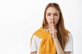 Close up of blond young woman shushing, press finger to lips and looking upset, hushing, say shhh telling to keep quiet Royalty Free Stock Photo