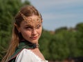 Close-up of blonde girl with blue eyes and elf ears wearing a green cape Royalty Free Stock Photo